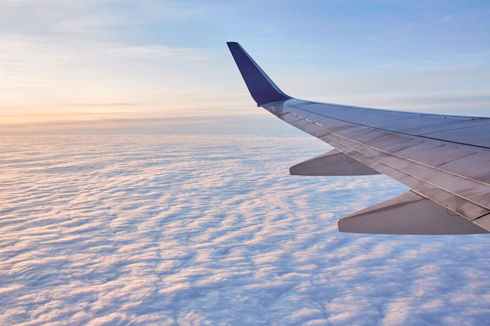 Ala di un aereo vista dal finestrino, sopra il mare e le nuvole