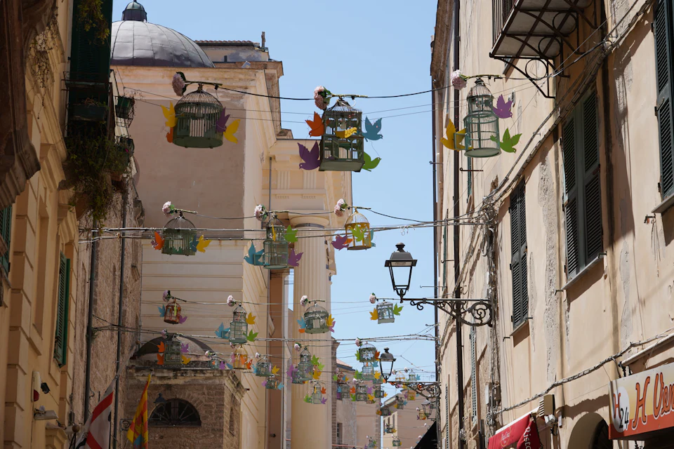 Vicolo del centro storico di Alghero con decorazioni colorate sospese tra le case